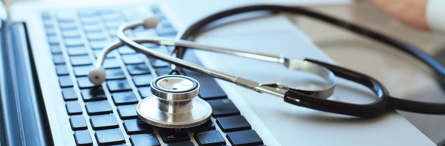 Stethoskop und Laptop auf einem Schreibtisch // Stethoscope and laptop on a desk