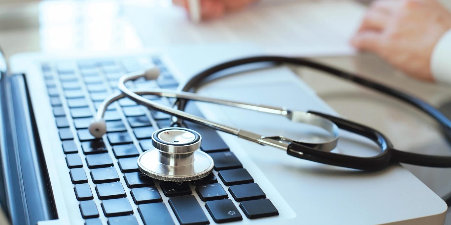 Stethoskop und Laptop auf einem Schreibtisch // Stethoscope and laptop on a desk