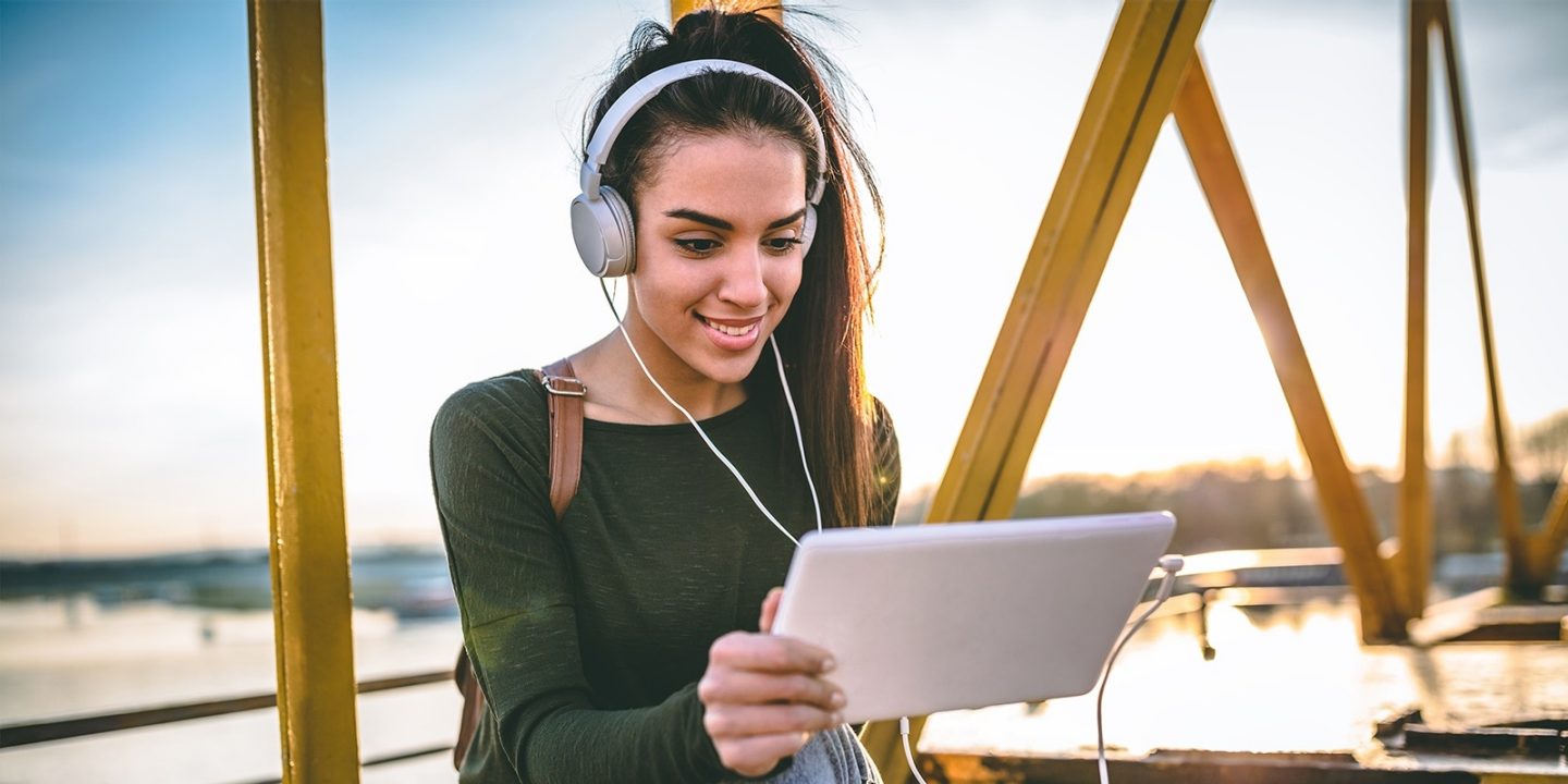 Young talented female student dressed in casual clothing sits on the top of the building and reading news on tablet pc.; Shutterstock ID 795642889; purchase_order: -; job: -; client: -; other: -